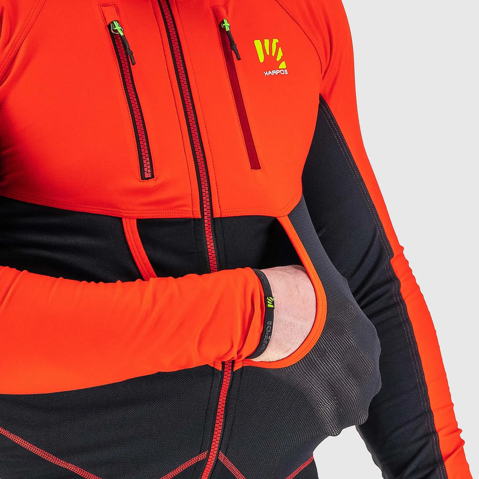 Detail einer orange-schwarzen Karpos-Jacke mit Brusttaschen und elastischem Ärmelabschluss