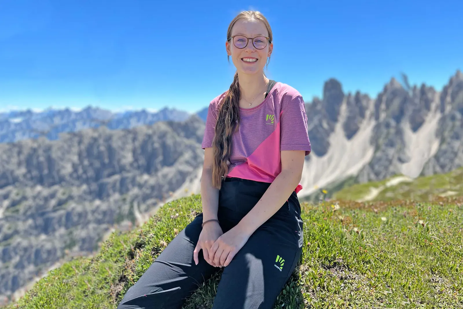 Luzia mit rosa Karpos-Shirt und langer dunkler Wanderhose in den Dolomiten