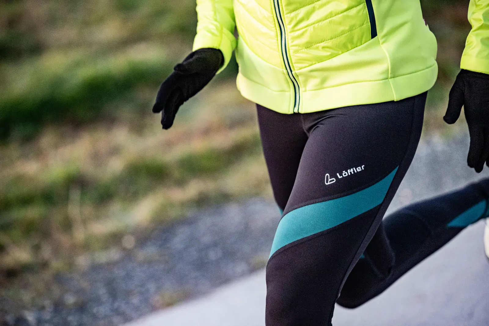 Laufhose mit türkisfarbenen Einsätzen, dazu eine gelbe Jacke und schwarze Handschuhe