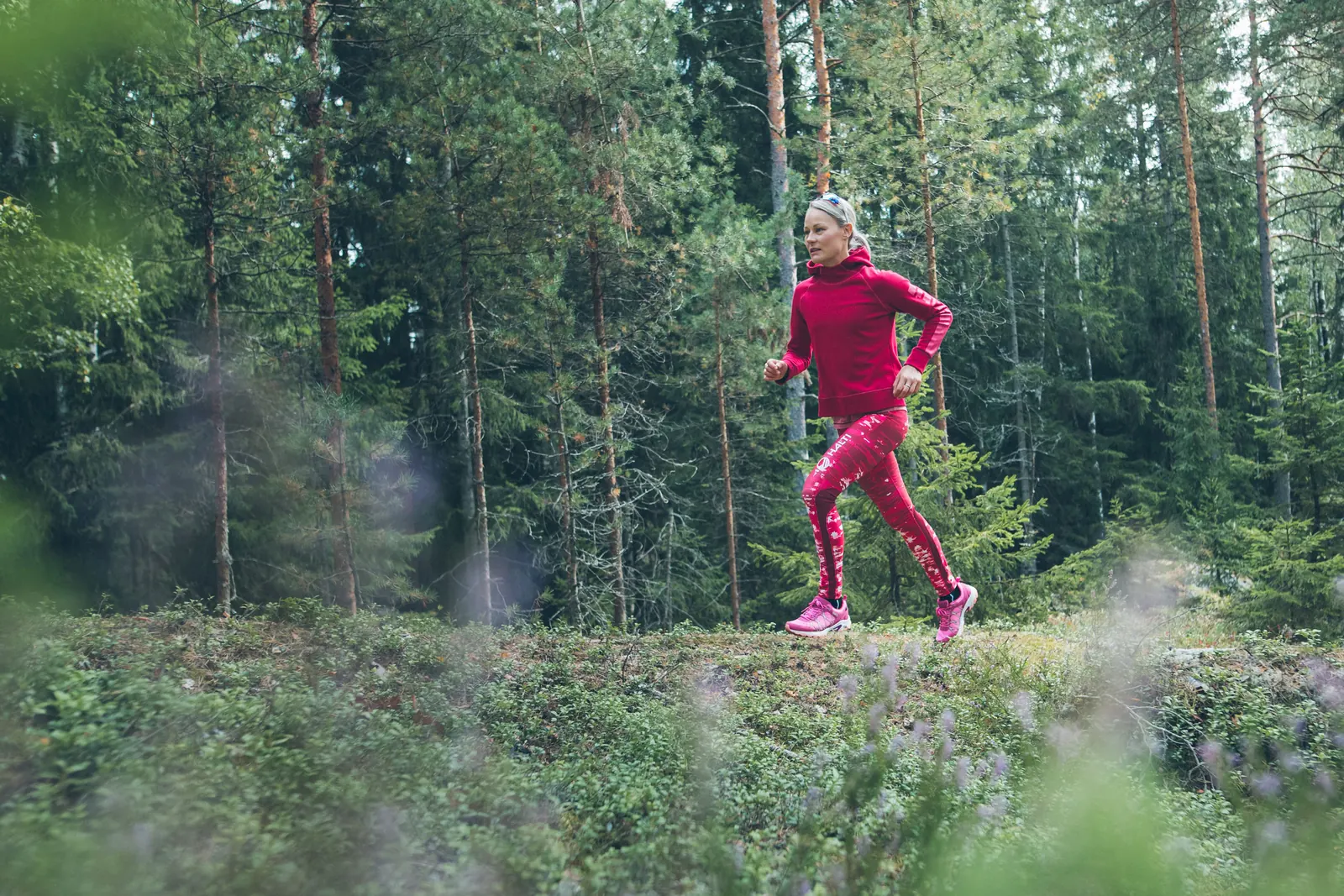 Läuferin in pinkfarbener Bekleidung auf einem schmalen Weg durch den Wald
