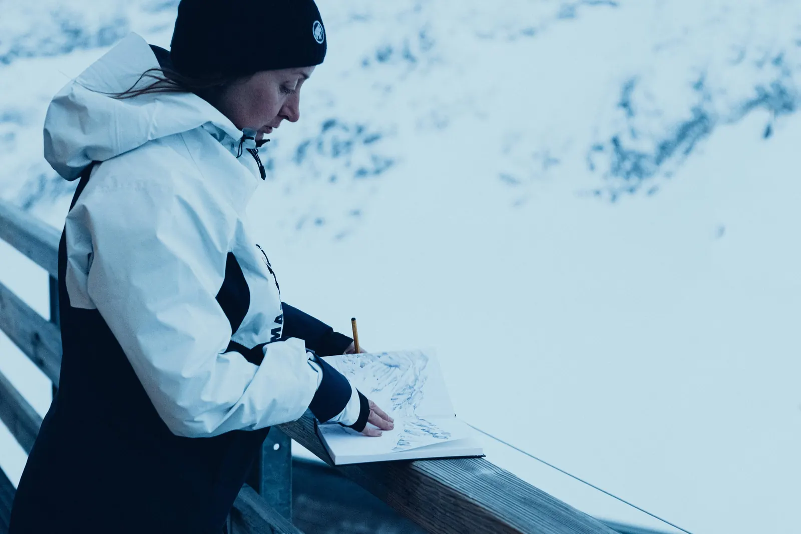 Skifahrerin in weißer und dunkelblauer La-Liste-Jacke mit sichtbarer Handgamasche beim Kartenlesen