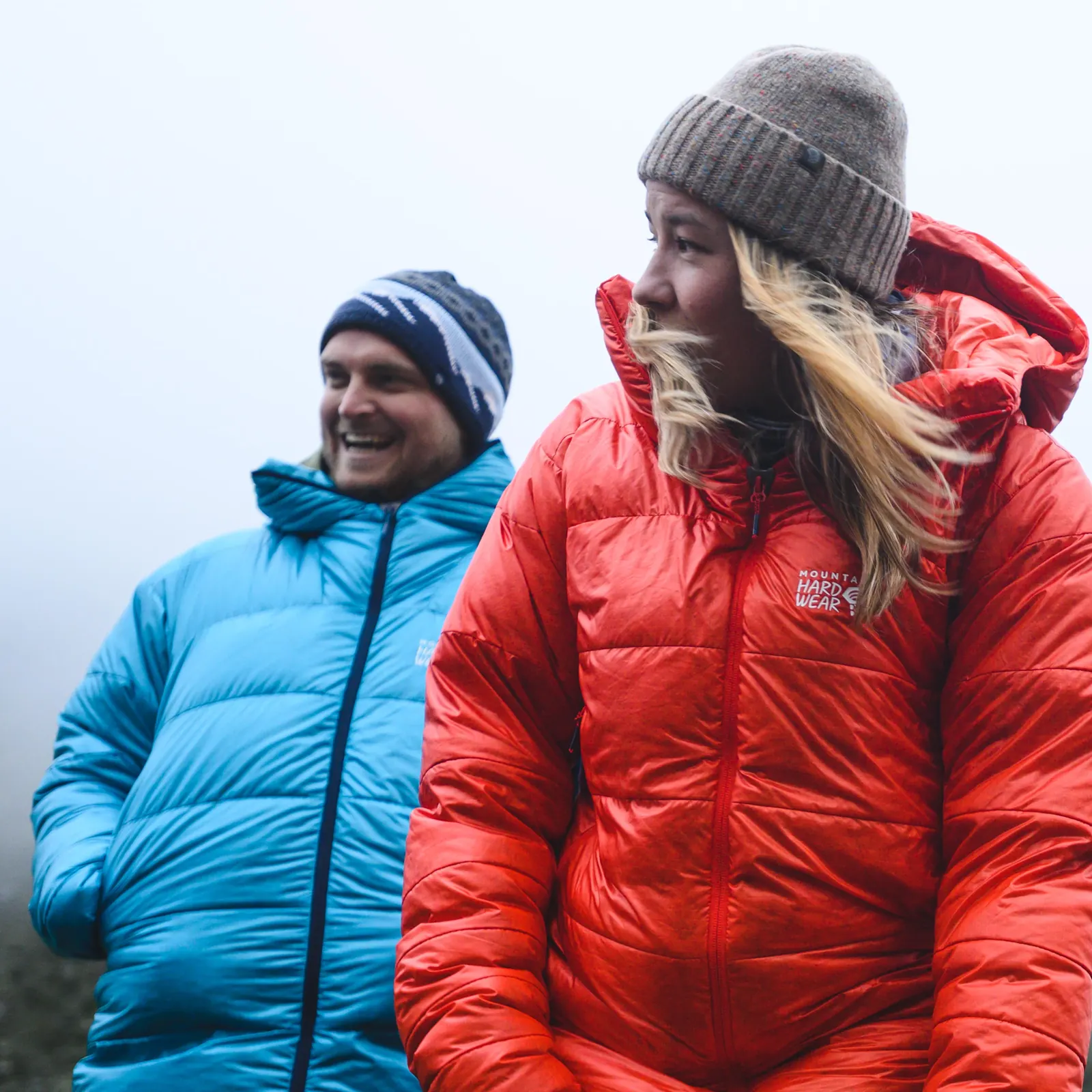 Zwei Personen in roter und blauer Daunenjacke mit Kapuze bei winterlichem Wetter