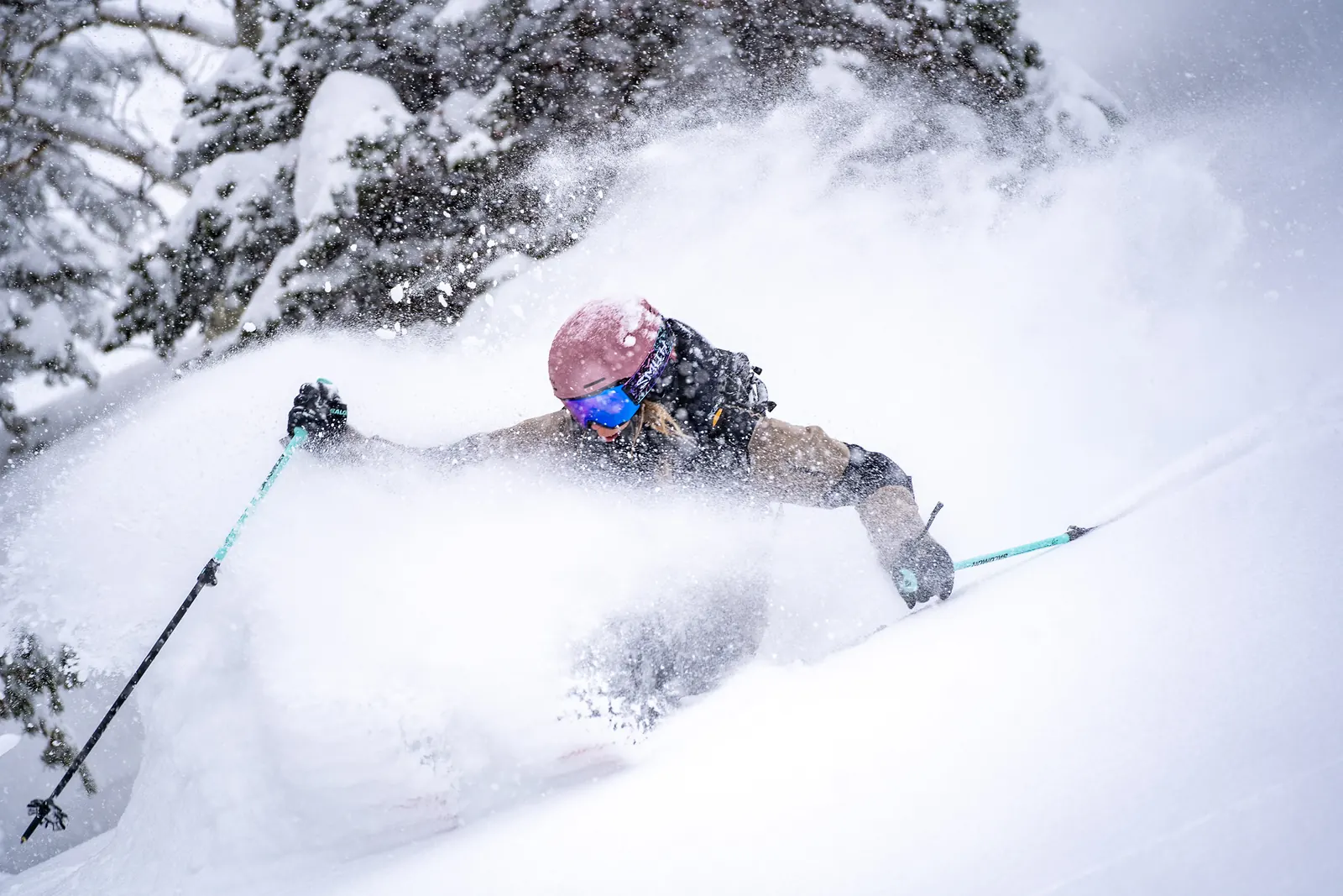 Skifahrer mit rosafarbenem Smith-Helm und Skibrille im Tiefschnee