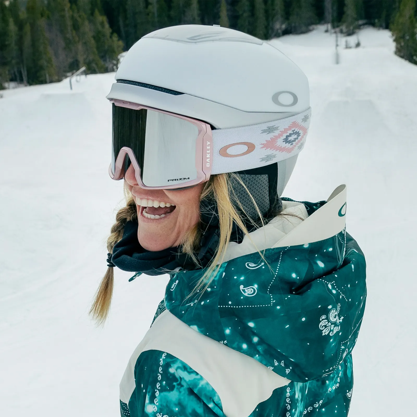 Wintersportlerin mit weißem Helm und Oakley-Skibrille mit gemustertem Band im Schnee