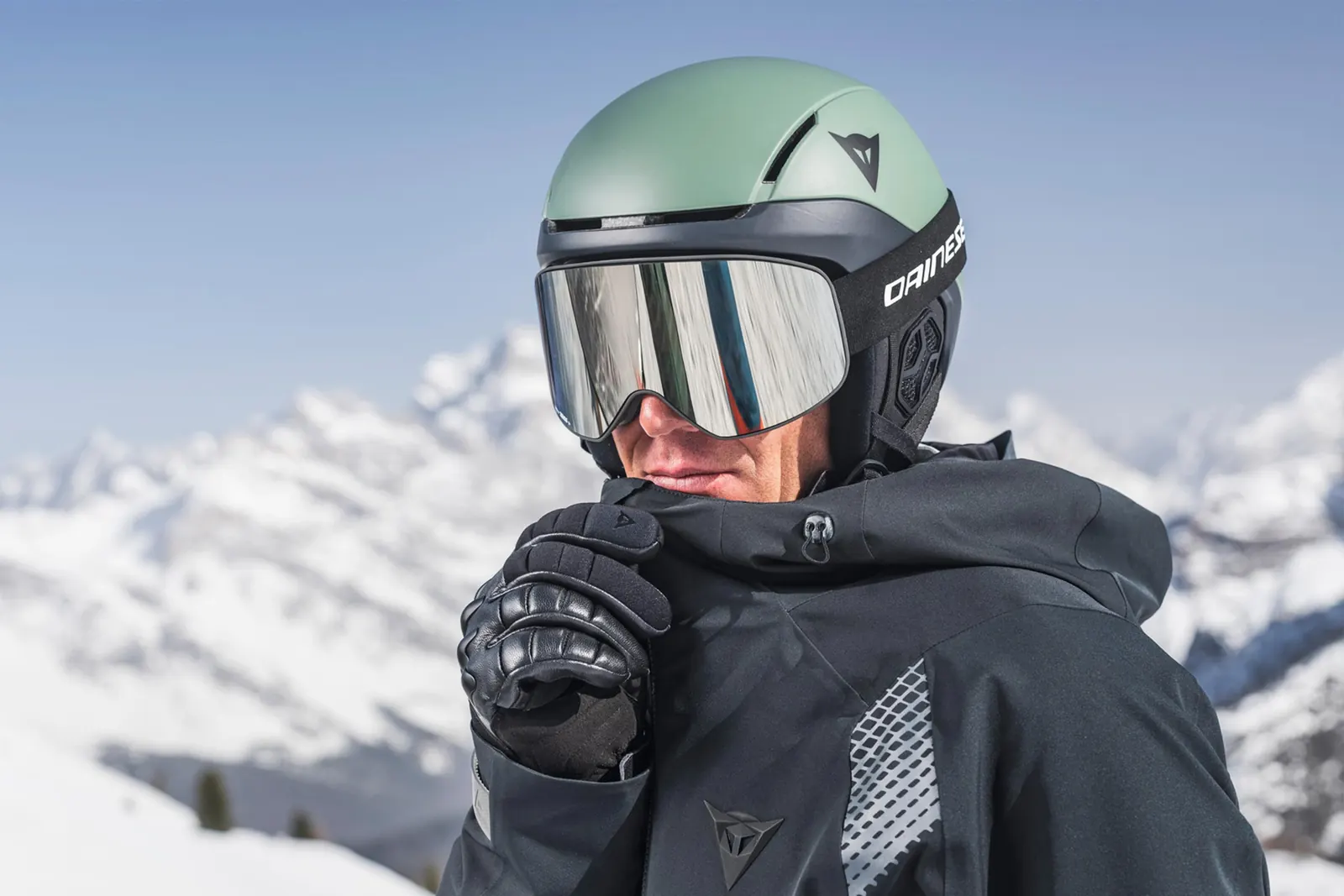 Person mit grünem Dainese Elemento, verspiegelter Skibrille und schwarzer Skijacke
