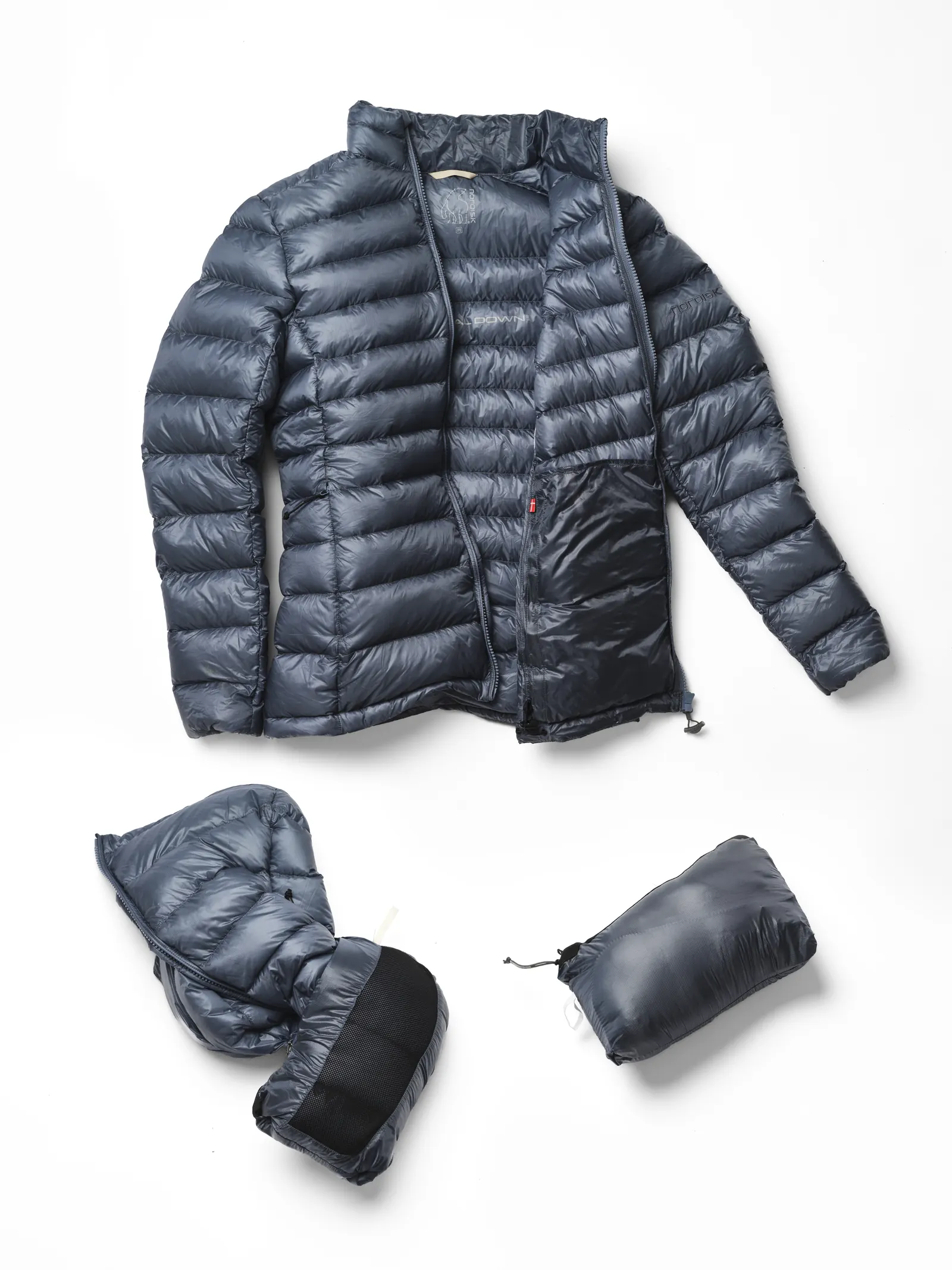 Nordisk Companyon Daunenjacke in Blue Mirage ausgebreitet neben der komprimierten, zusammengepackten Version im Packbeutel