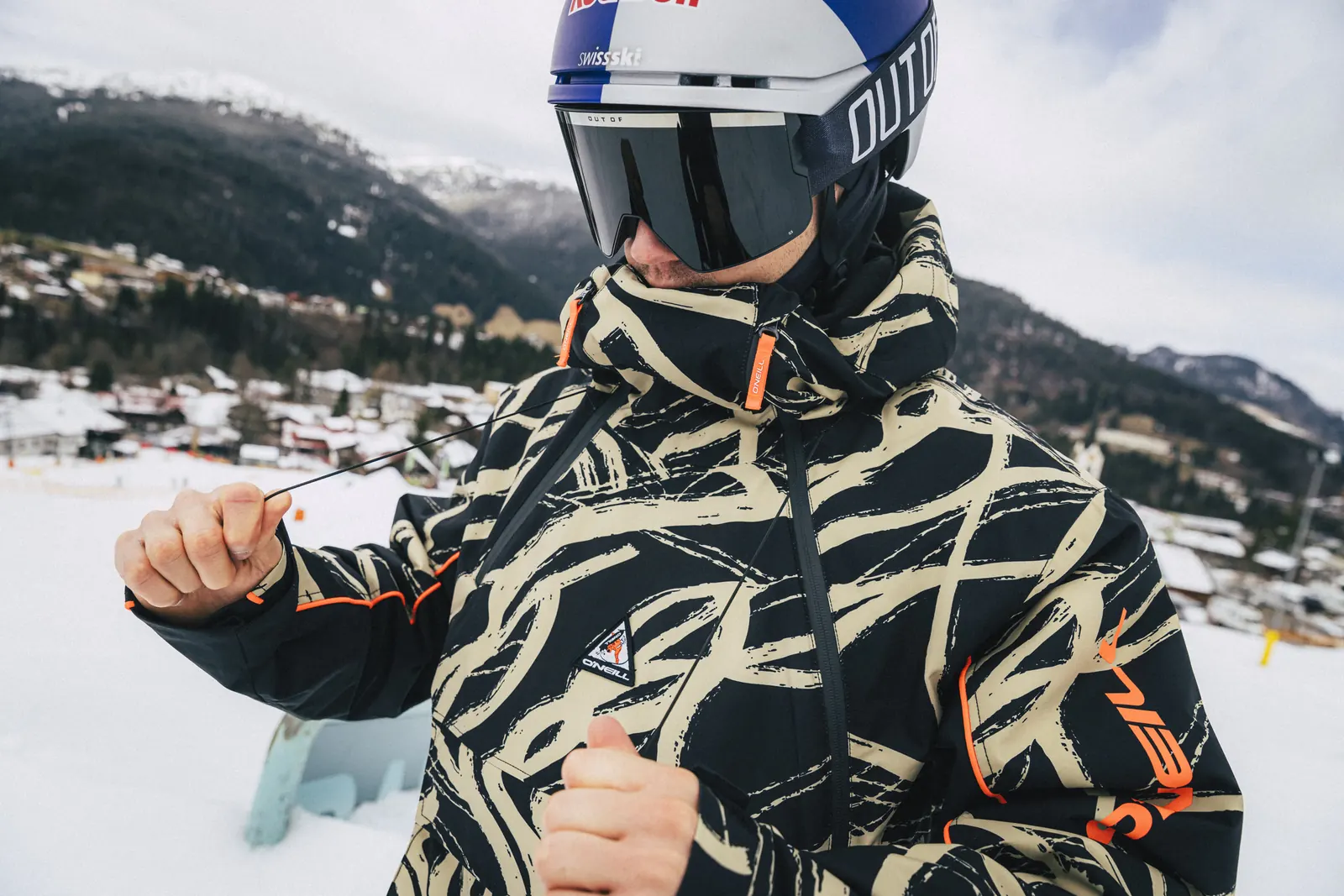Snowboarder in der O'Neill FWC'Play Asymmetric Snow Jacket beige snowtracks zieht am Hang die Handschuhe an