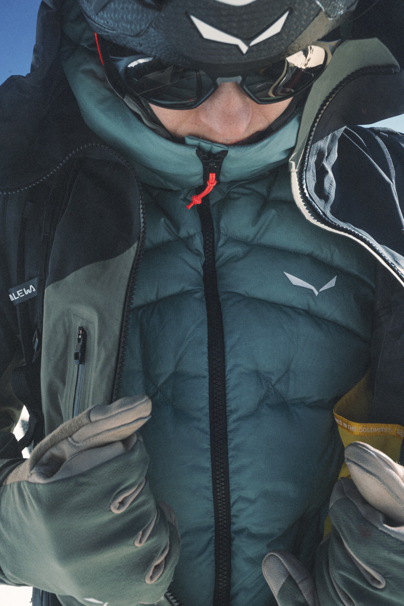 Nahaufnahme einer dunkelgrünen Daunenjacke mit sichtbarer Kammersteppung und Salewa-Logo