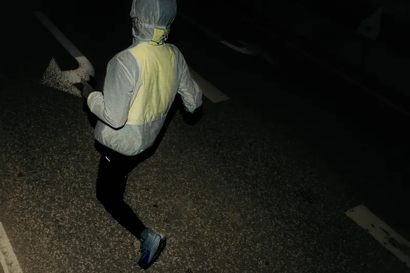 Läufer in der reflektierenden Craft Lumen Jacke bei Nacht auf der Straße