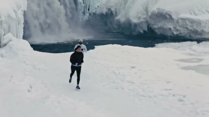 Läuferin vor einem gefrorenen Wasserfall im Schnee
