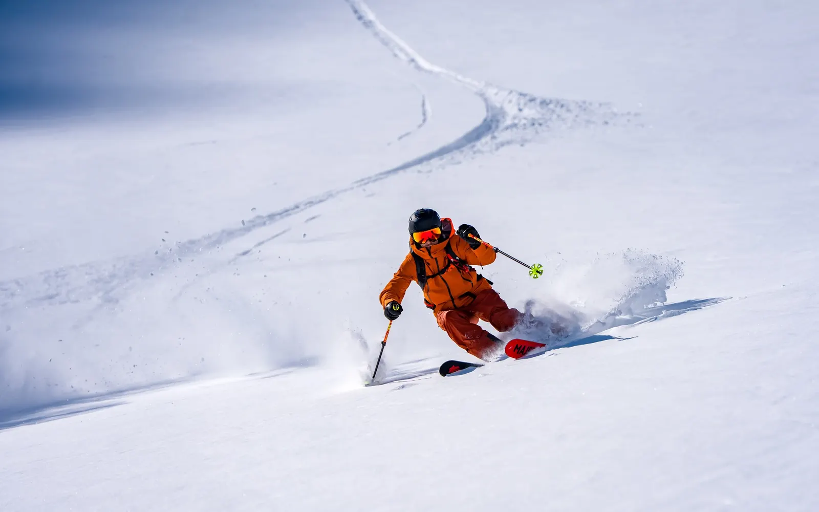 Freerider in orange Helly Hansen ski wear skiing through deep powder