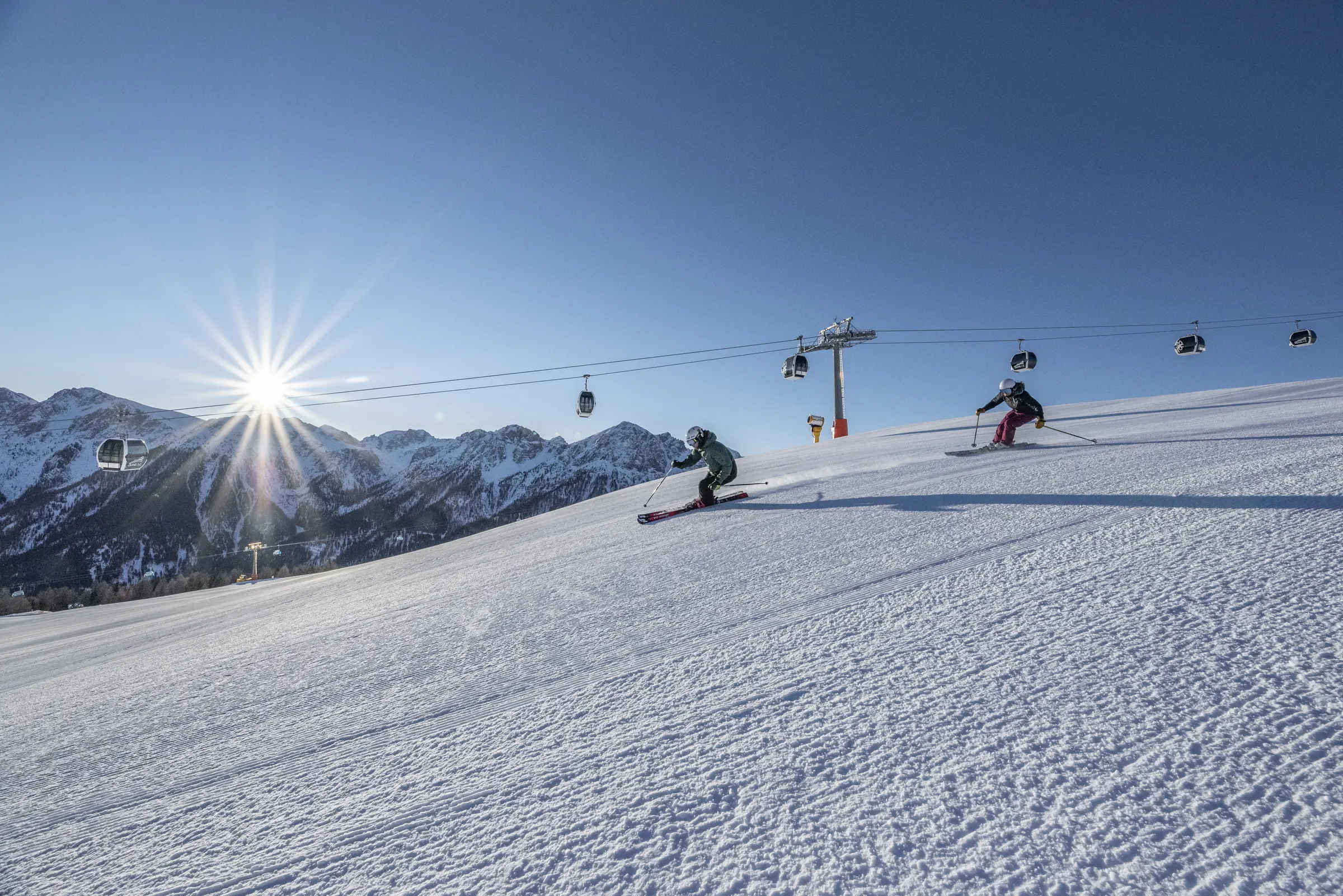 Winter in Kronplatz: Präparierte Piste mit Gondelbahn und Dolomitengipfeln
