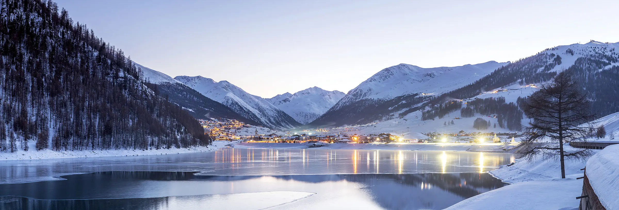 Winter in Livigno: Livigno in der Dämmerung über dem zugefrorenen Stausee
