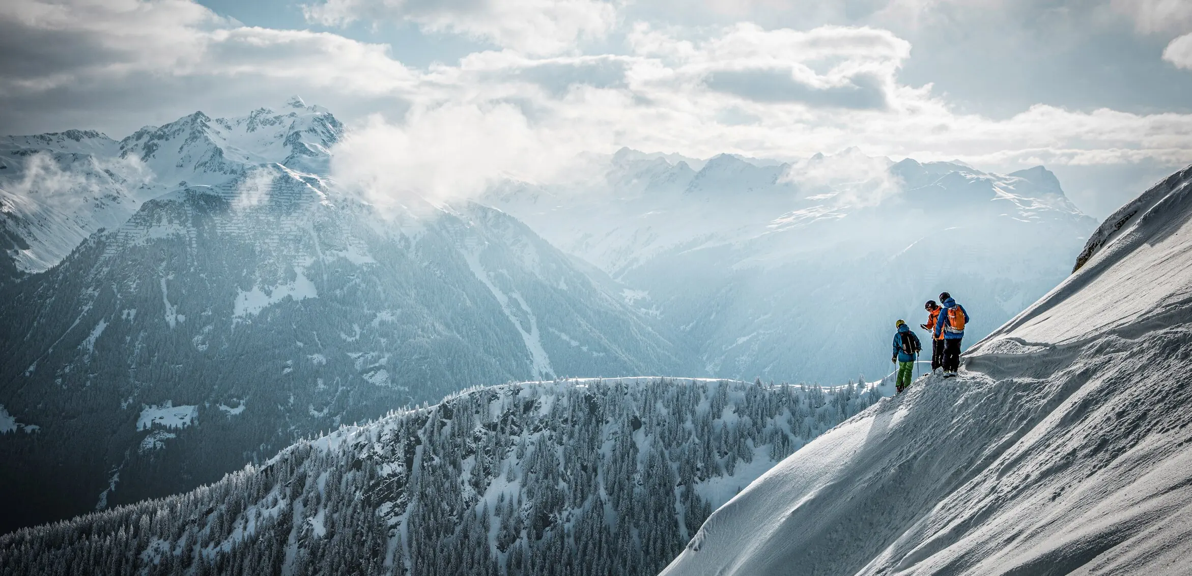 Winter in Montafon: Verschneite Gipfel über dem Montafon, drei kleine Freerider von hinten