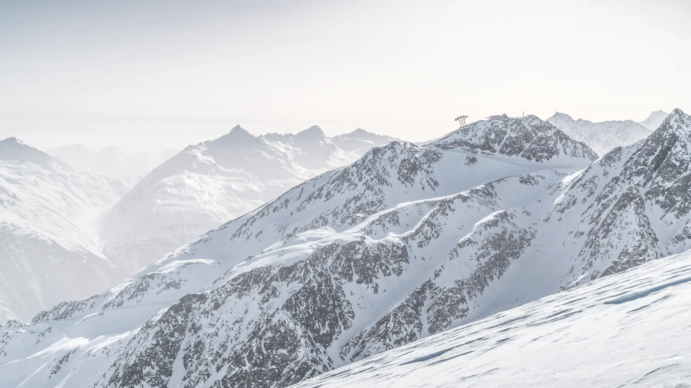 Hotels von Hochsölden an den verschneiten Skipisten oberhalb von Sölden, dahinter die Ötztaler Berge