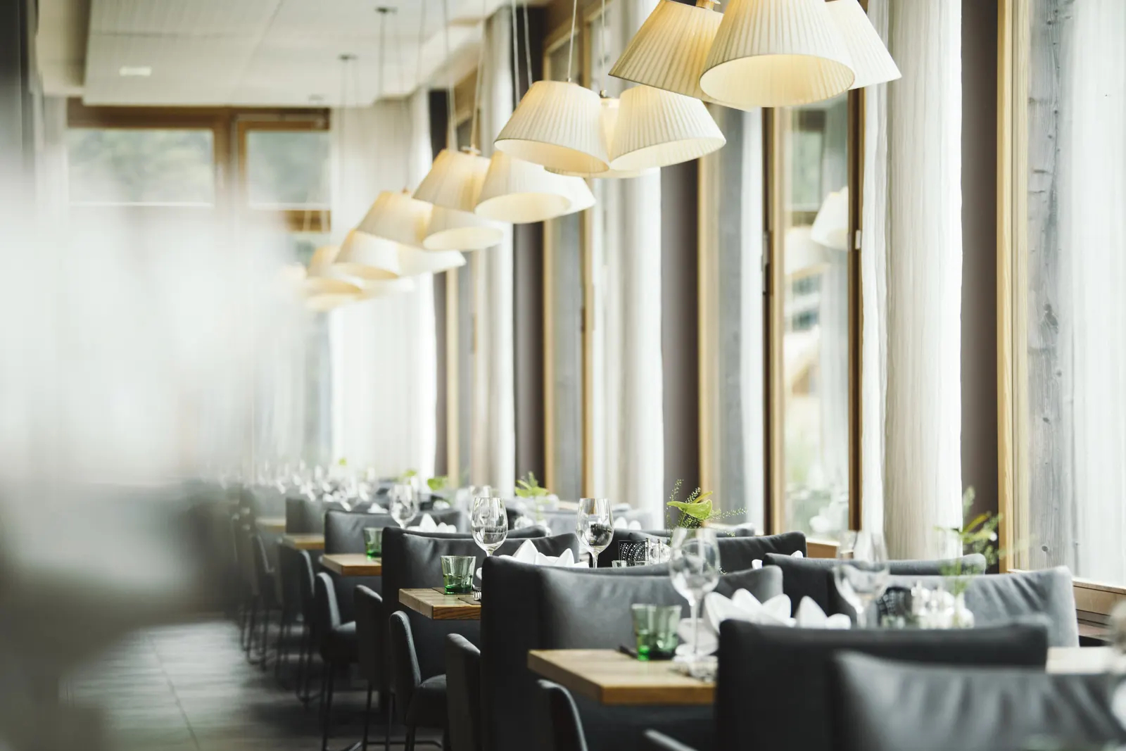 Restaurant im Almhof Family Resort mit gedeckten Tischen und Fensterfront