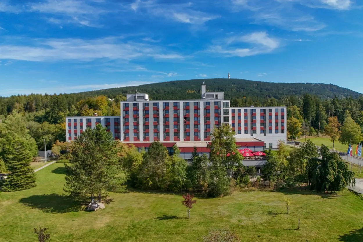 Hotel Kaiseralm in Bischofsgrün mit Garten, dahinter der bewaldete Ochsenkopf mit Sendeturm