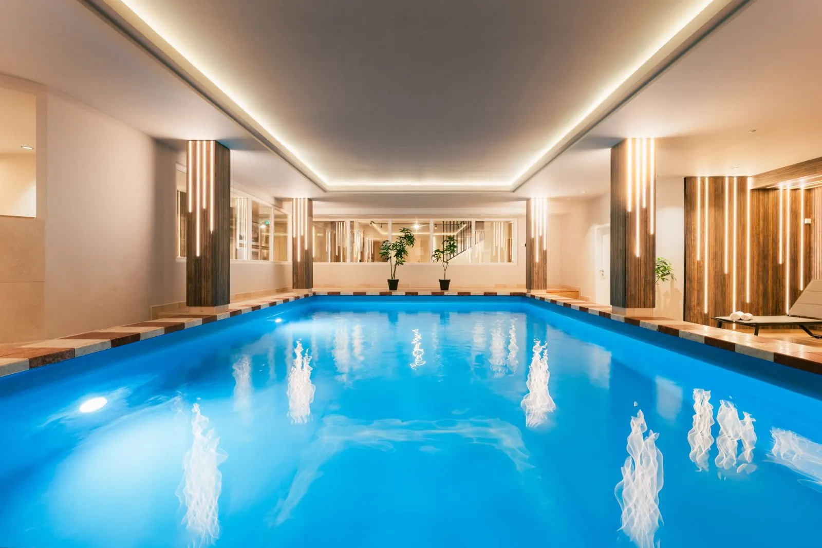 Beleuchtetes Hallenbad im MONDI Hotel Axams mit Holzverkleidung