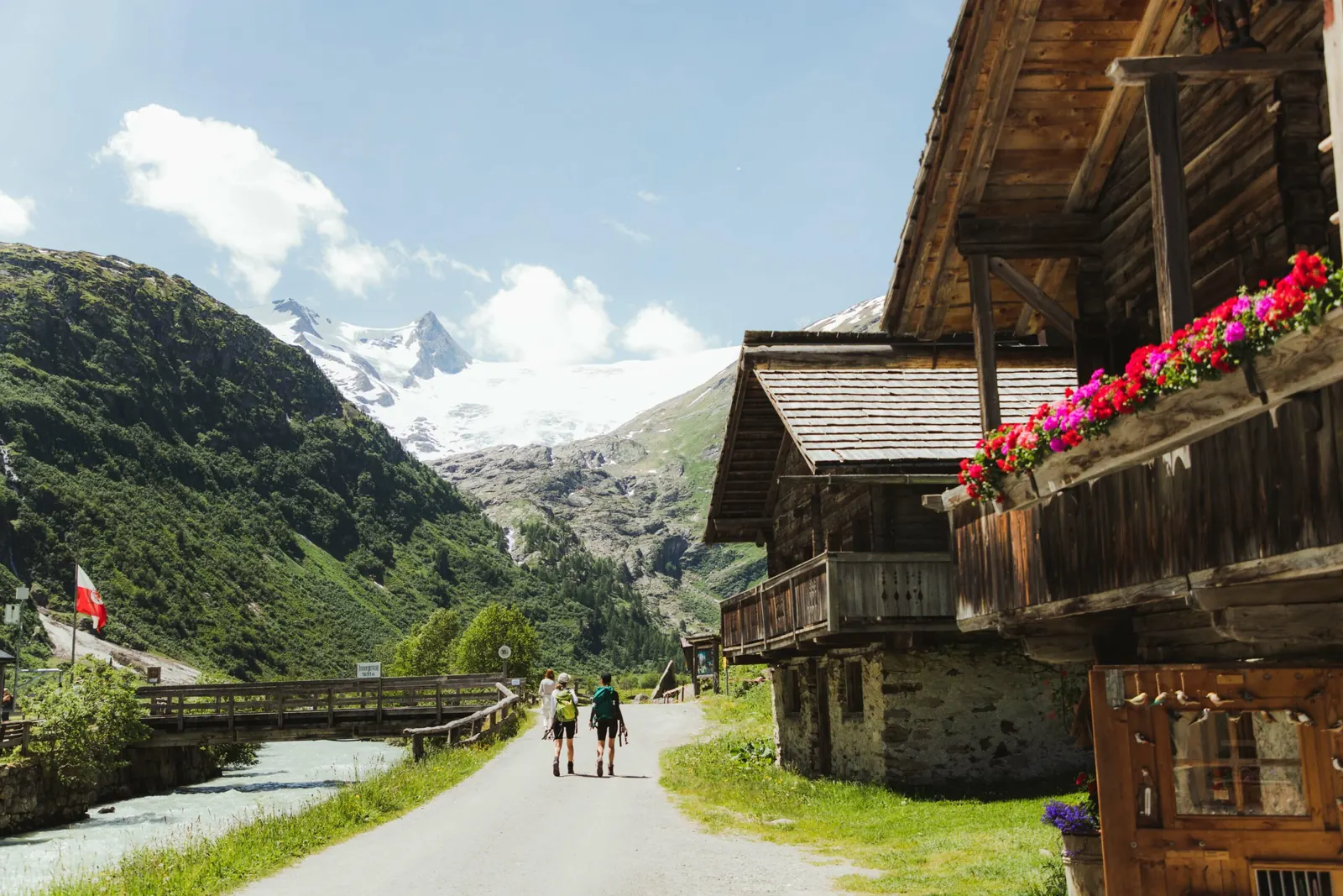 Wanderer zwischen Holzhäusern in Innergschlöss mit Blick zum Schlatenkees