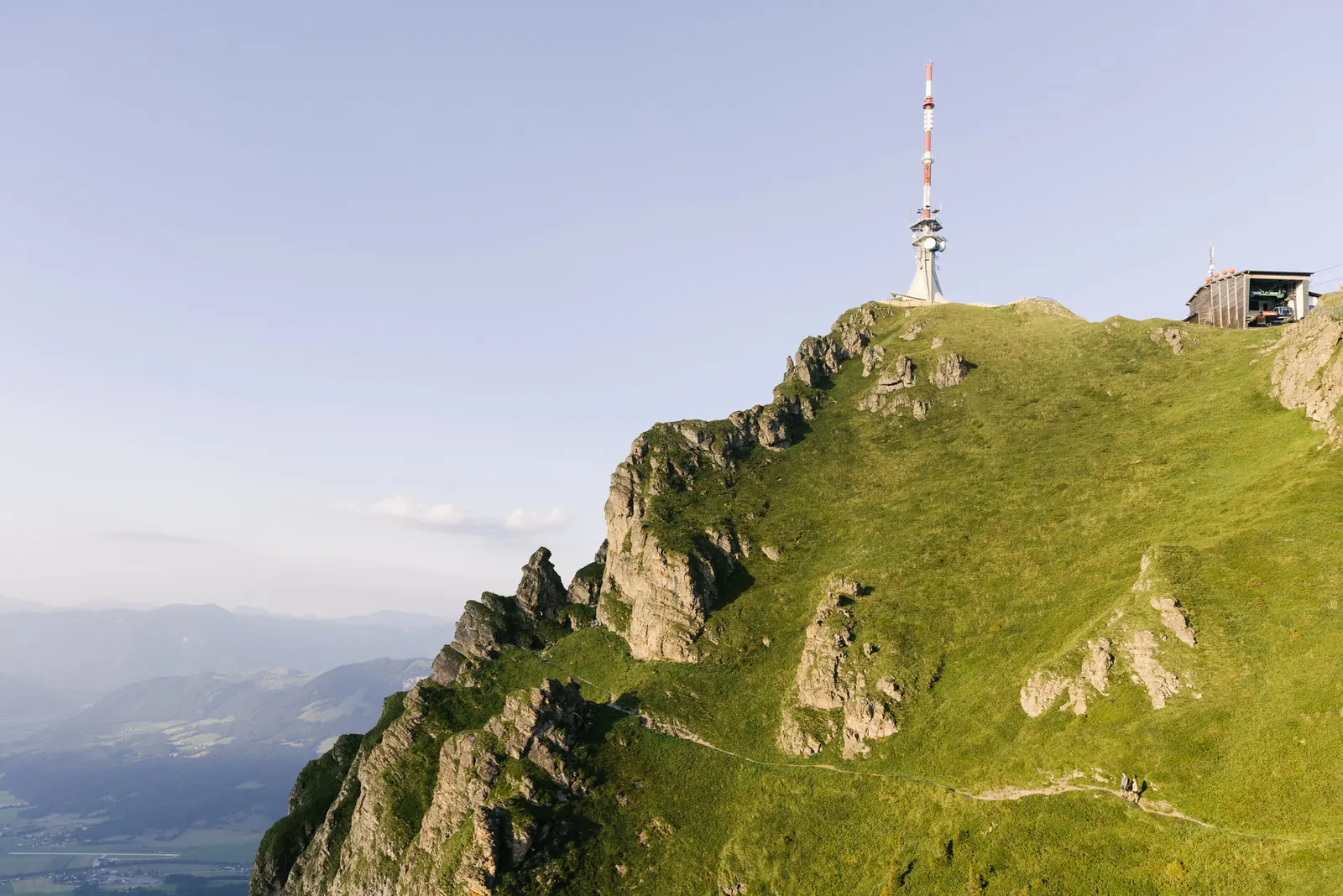 Grüne Gipfelflanke des Kitzbüheler Horns mit Felskante und Sendemast