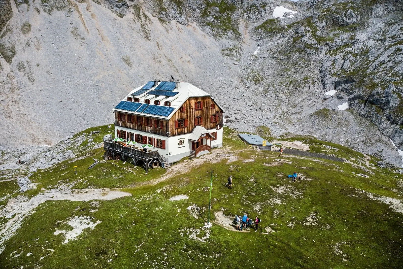 Guttenberghaus auf einem grünen Rücken unter hellen Felswänden