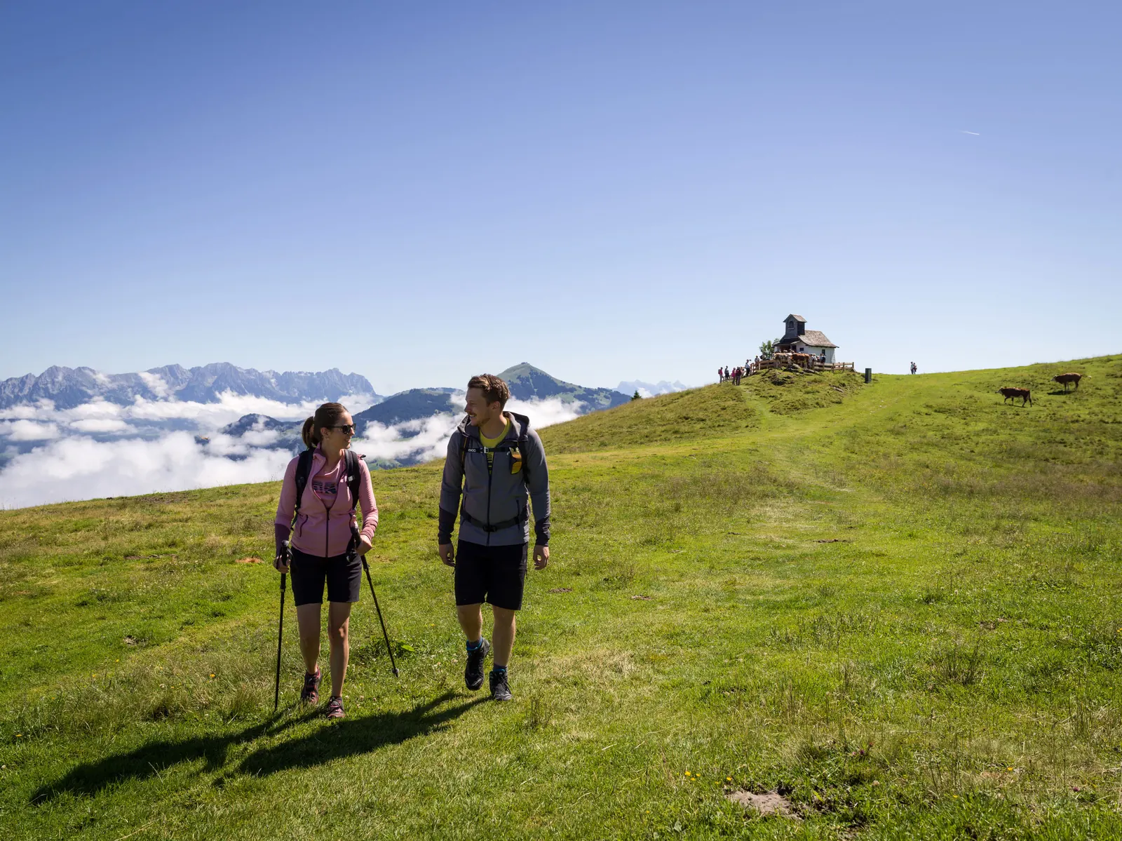 Wandernde auf grünen Almwiesen am Markbachjoch mit Kapelle und Hütten