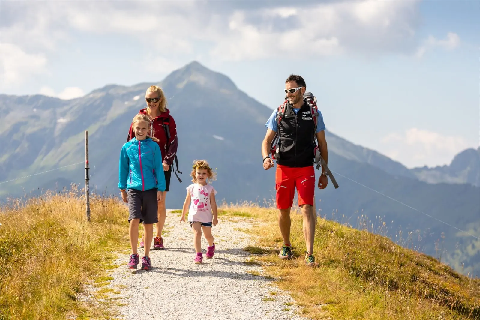 Familie auf einem Sommerwanderweg am Schatzberg vor grünen Bergkämmen
