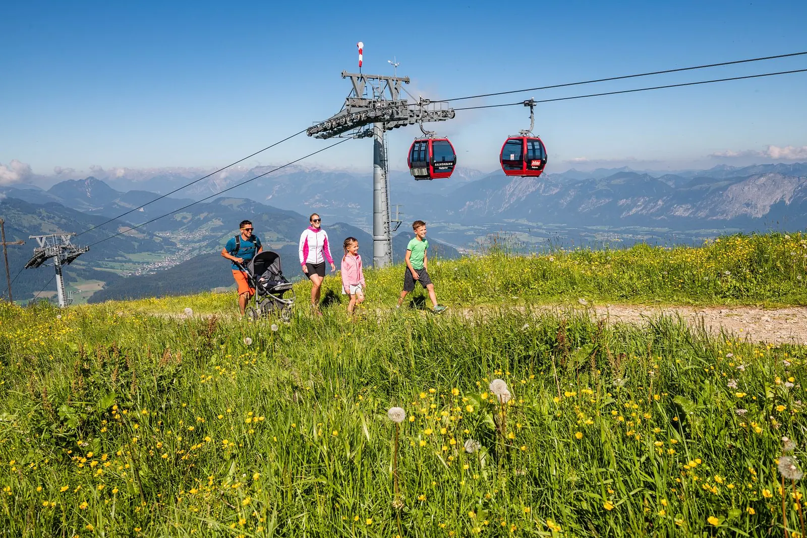 Familie auf einer Sommerwiese an der Hohen Salve mit Gondeln im Hintergrund