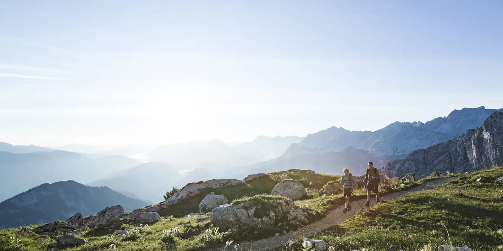 Zwei Wandernde im Morgenlicht auf einem Bergweg im Gebiet Garmisch-Classic