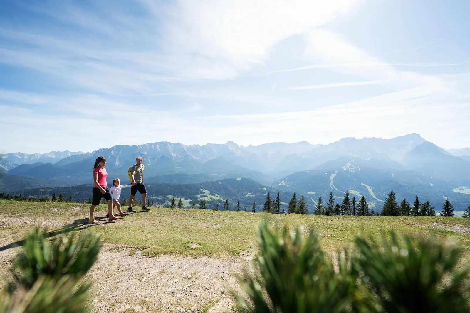 Familie auf dem sonnigen Gipfelplateau des Wank mit Alpenpanorama