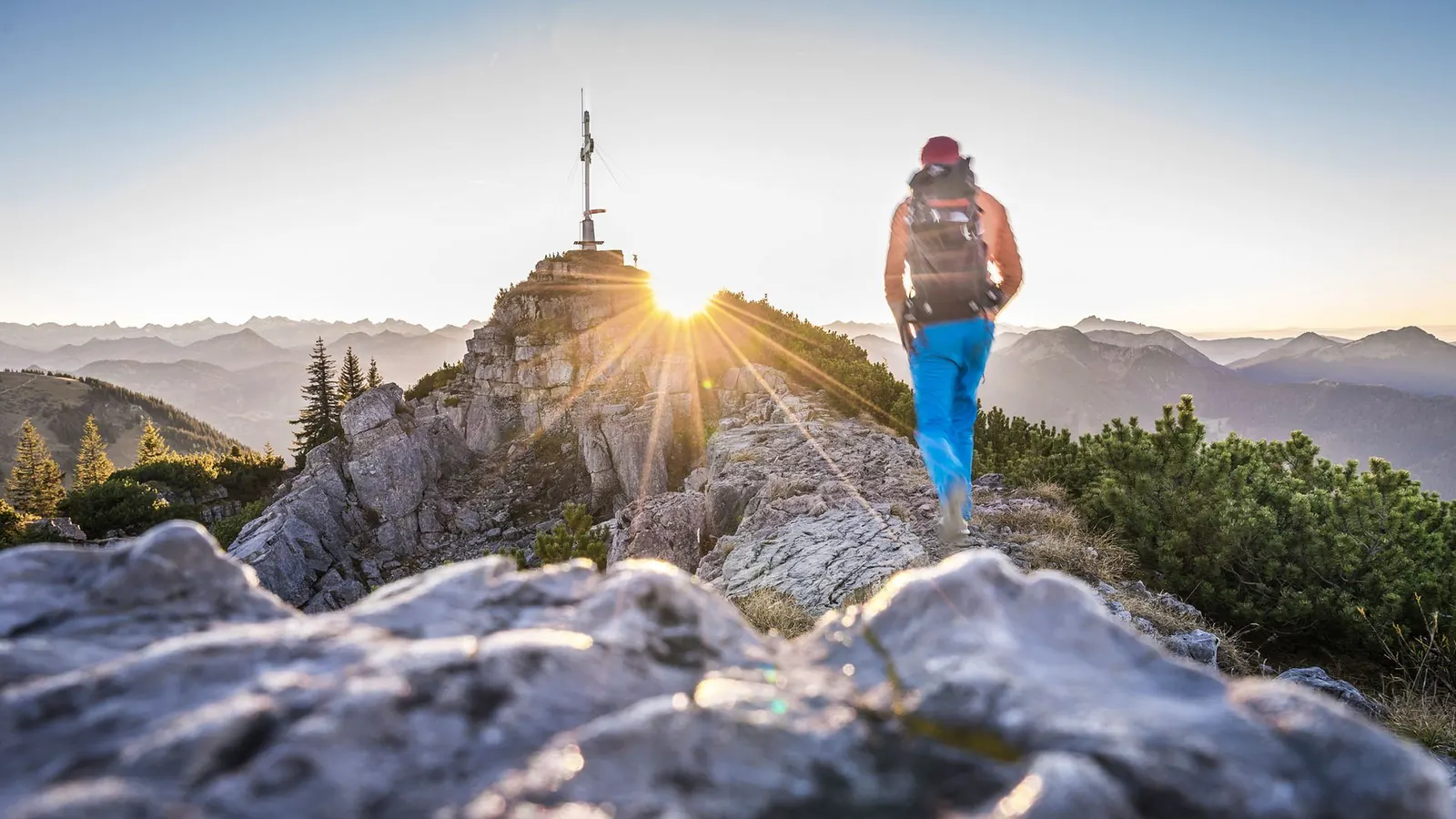 Wanderin kurz vor dem Gipfelkreuz des Wallbergs bei Sonnenaufgang