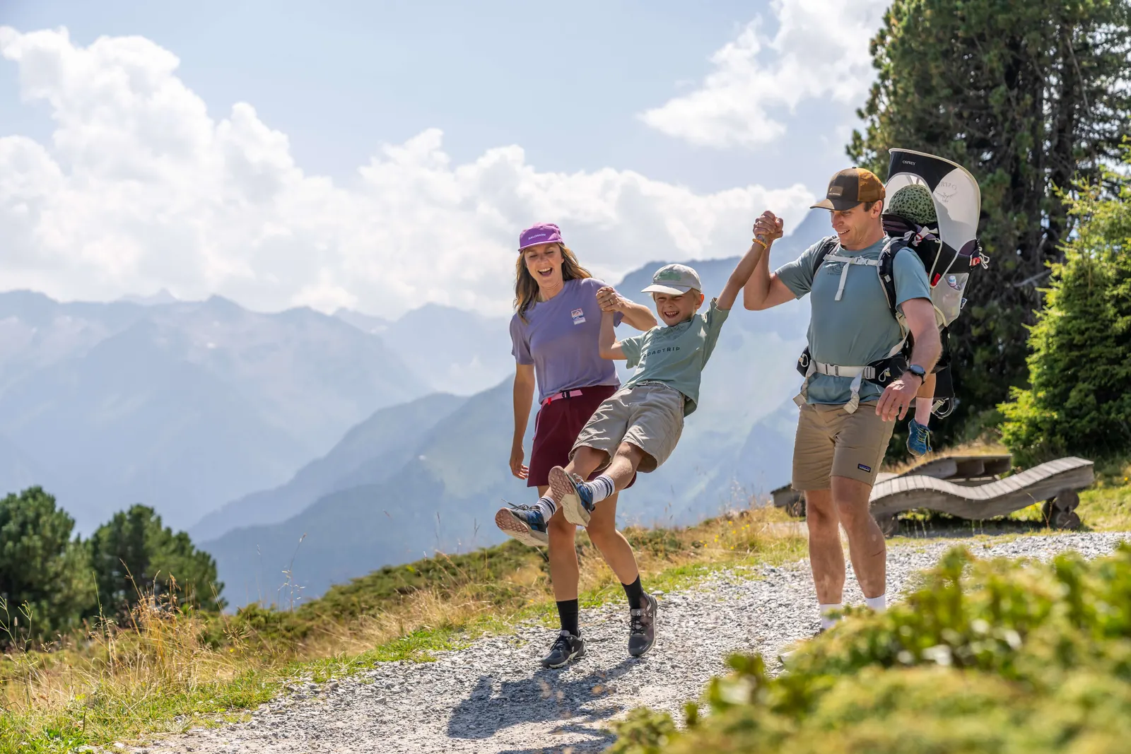 Familie mit Kindertrage auf einem sonnigen Wanderweg am Penken