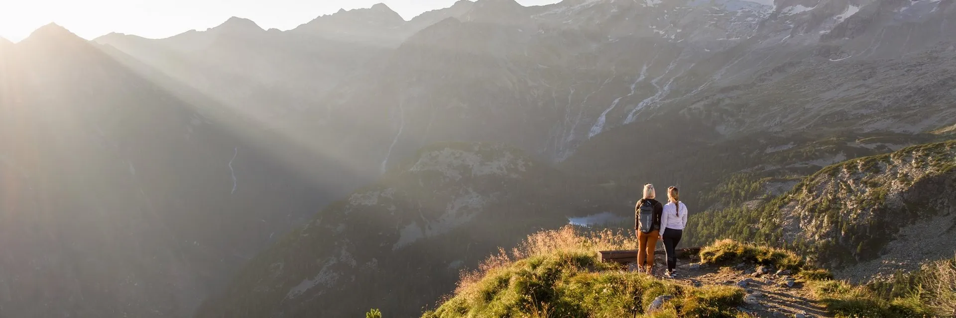 Wanderinnen am Graukogel mit Blick auf Bergkämme im Morgenlicht