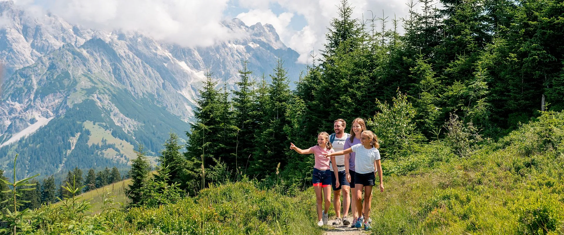 Familie auf einem grünen Wanderweg bei Dienten vor den Hochkönigwänden