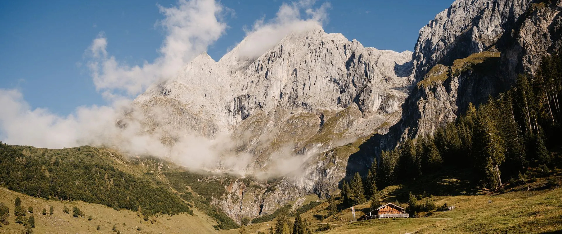 Helle Felswände des Hochkönigmassivs über grünen Berghängen