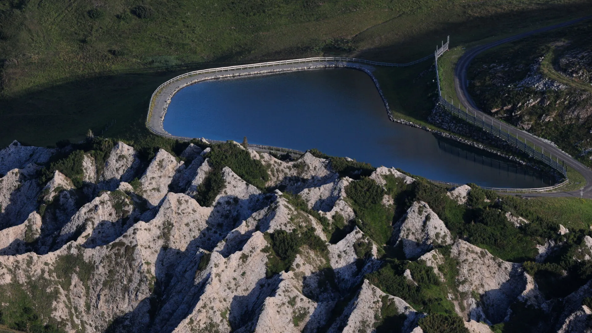 Helle Gipsmulden mit grünen Wiesen vor dem Kriegerspeichersee oberhalb von Oberlech.