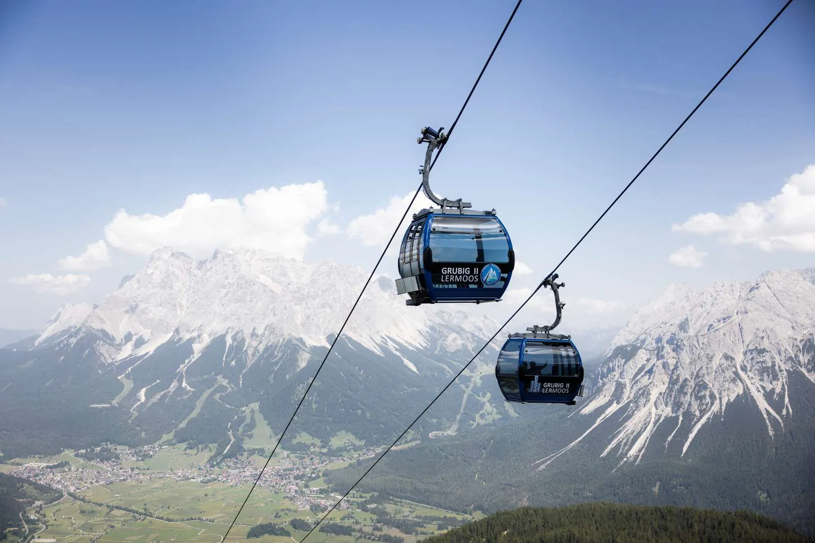 Gondeln der Grubigsteinbahn vor dem Ehrwalder Becken und dem Wettersteinmassiv im Sommer.