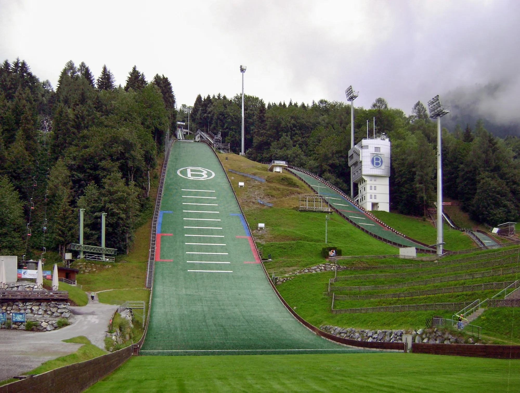 Aufsprunghang der Paul-Außerleitner-Schanze in Bischofshofen im Sommer mit grüner Matte, Kampfrichterturm und Tribünenstufen