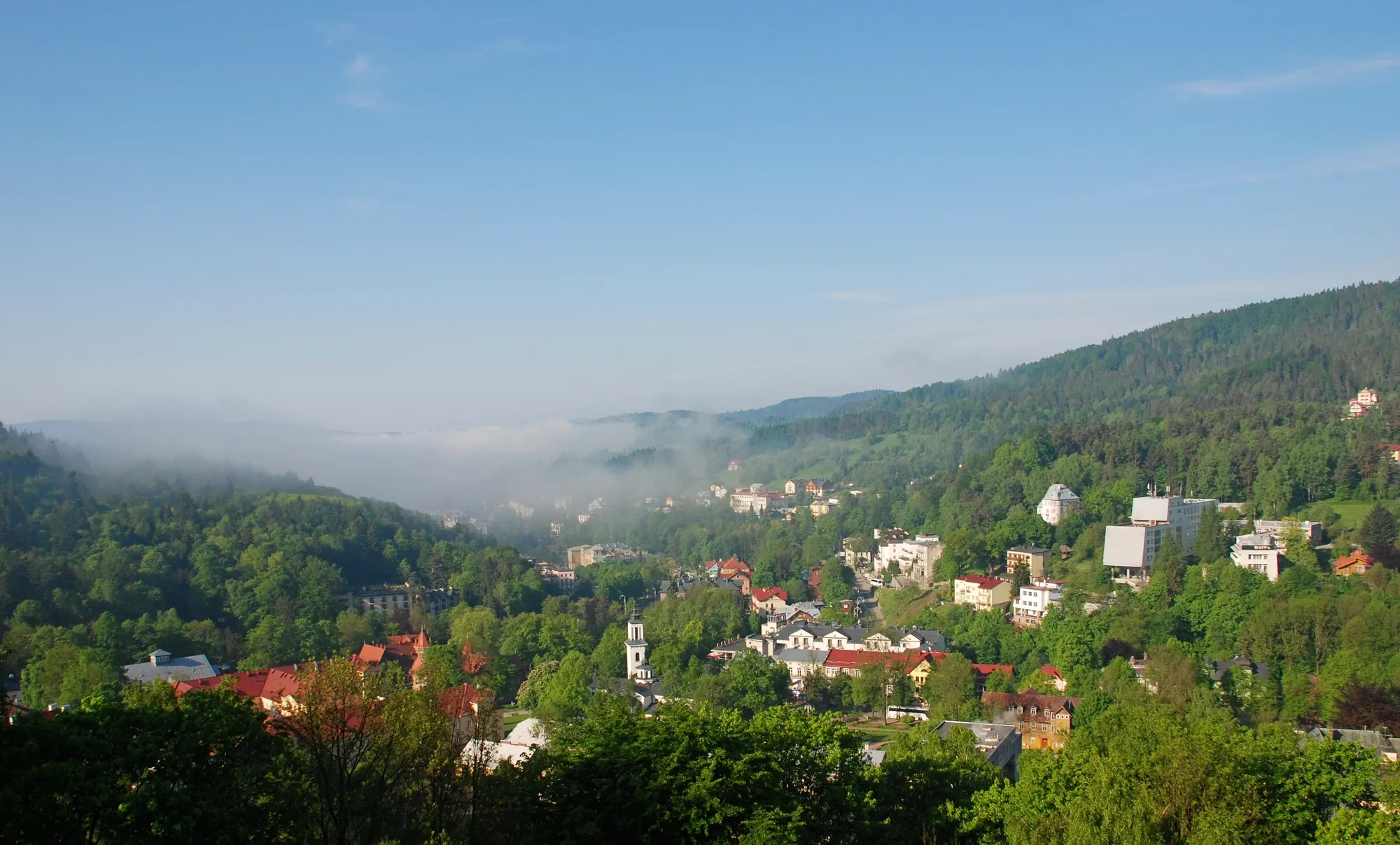 Krynica-Zdrój im Frühling mit Villen und Kurgebäuden im grünen Tal, Morgennebel zwischen bewaldeten Hügeln
