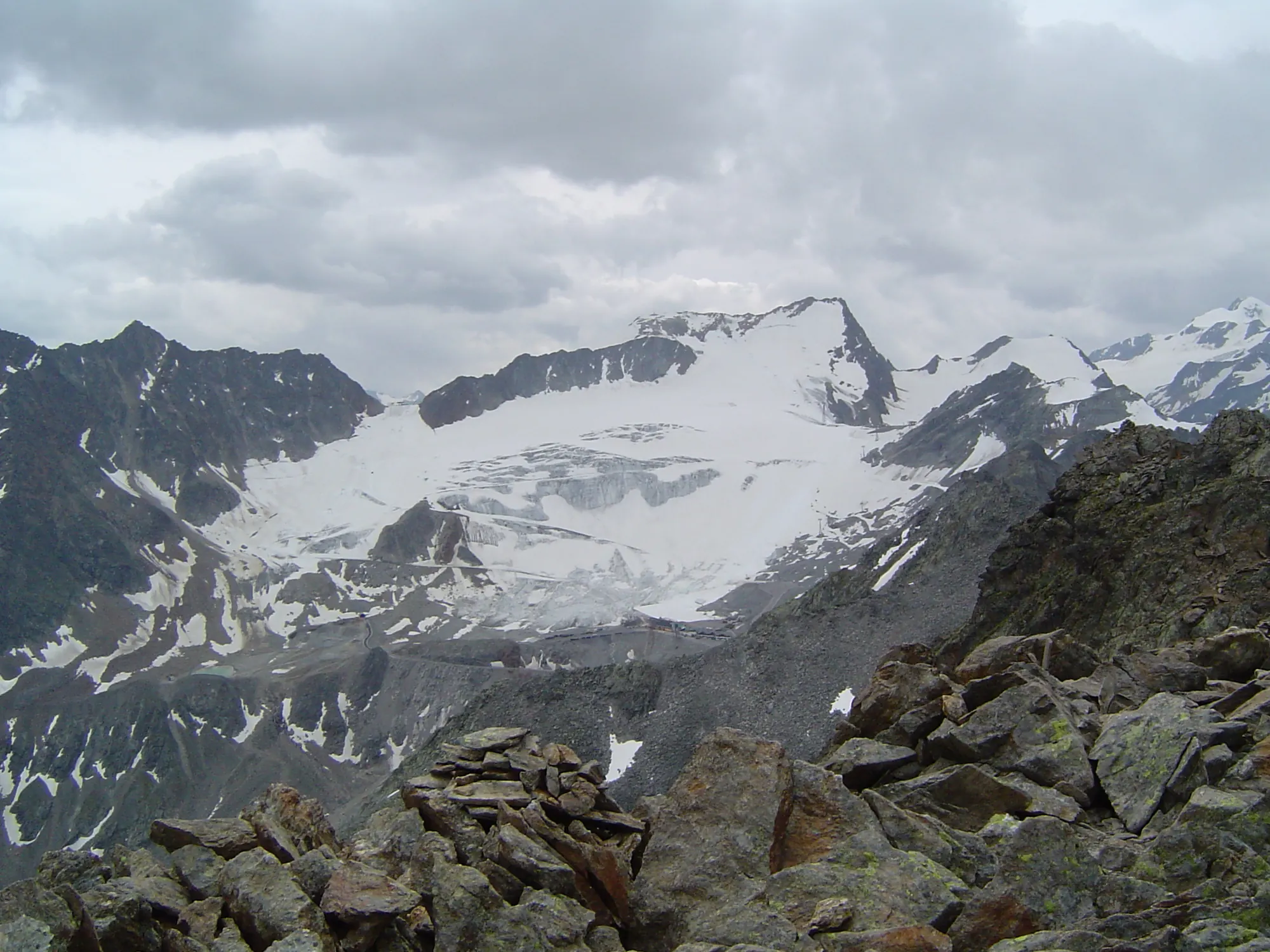 Rettenbachferner in den Ötztaler Alpen mit Gletscherfläche, gesehen von einem felsigen Gipfel unter Wolken