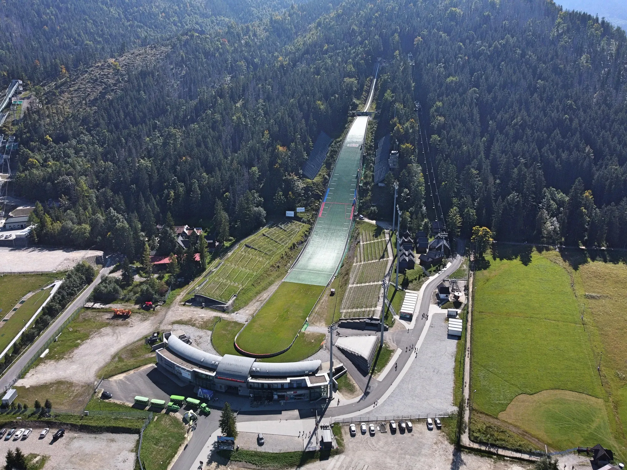Luftaufnahme der Großschanze Wielka Krokiew in Zakopane mit Mattenbelag, Tribünen und Wald im Spätsommer