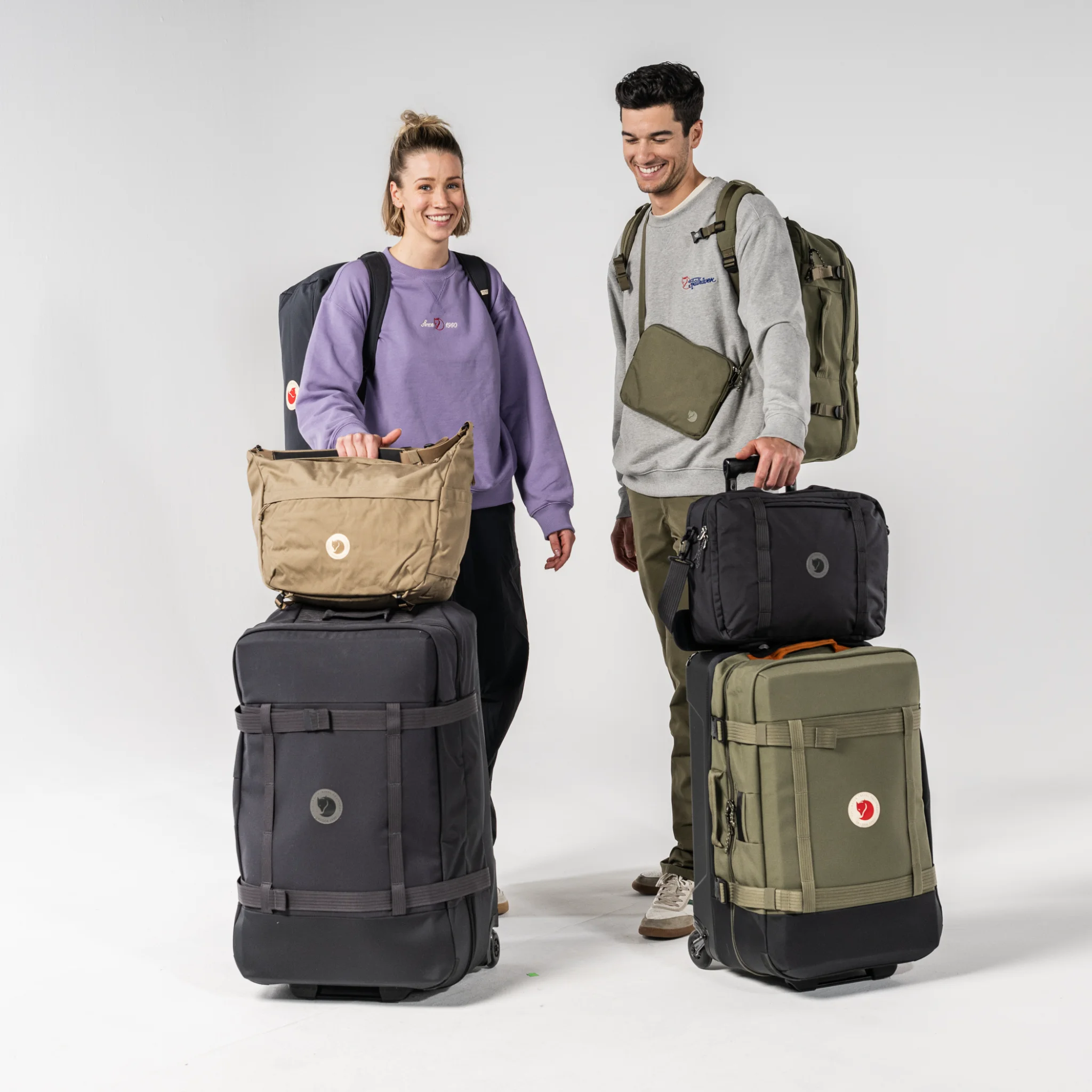 Fjällräven Taschen-Kollektion: Reiserucksack, Duffel und Roller in gedeckten Farben auf hellem Holztisch