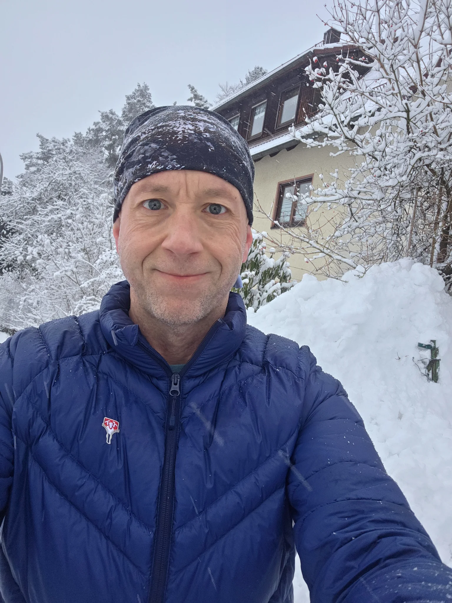 Mann in leichter Steppjacke beim Schneeräumen bei Minustemperaturen – Praxistest der Grüezi bag Senseful DownWool® Jacket