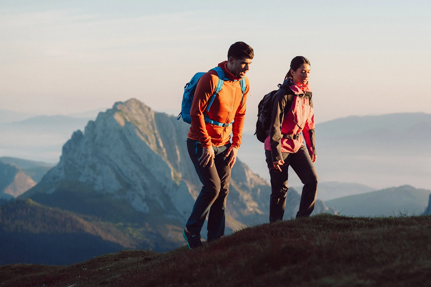 Wanderer mit Rucksack auf einem Bergpfad im Baskenland bei Sonnenaufgang