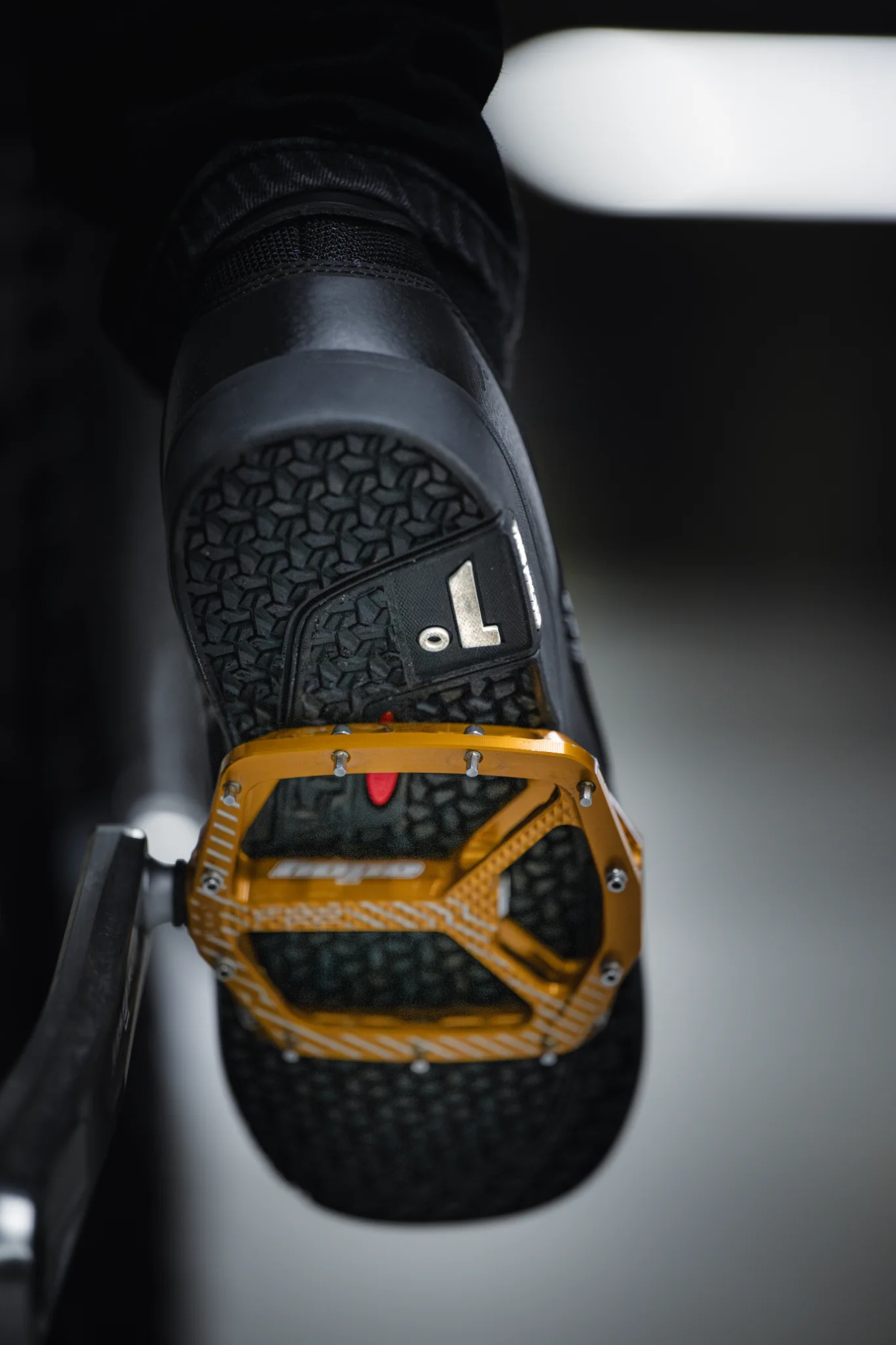 Detailaufnahme einer MTB-Flatpedal-Sohle mit hexagonalen Stollen auf einer schwarzen Aluminium-Plattformpedale mit Pins.