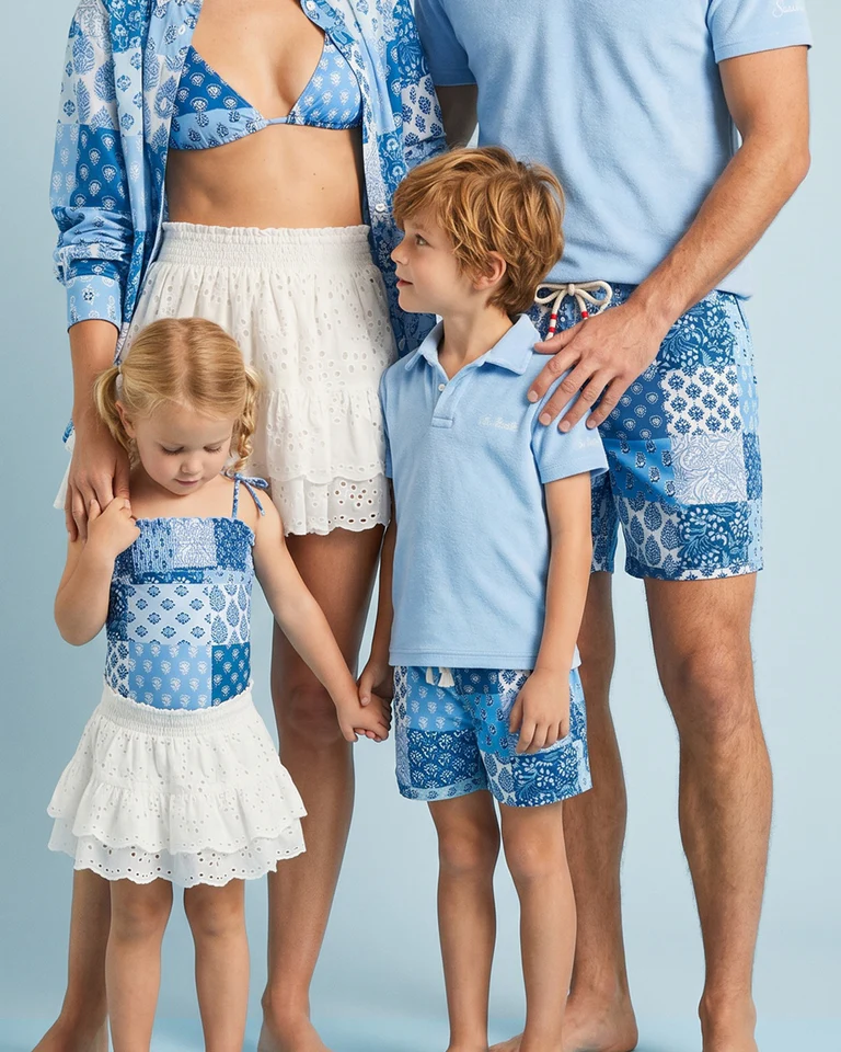 Familie in aufeinander abgestimmten blauen Patchwork-Outfits von MC2 Saint Barth