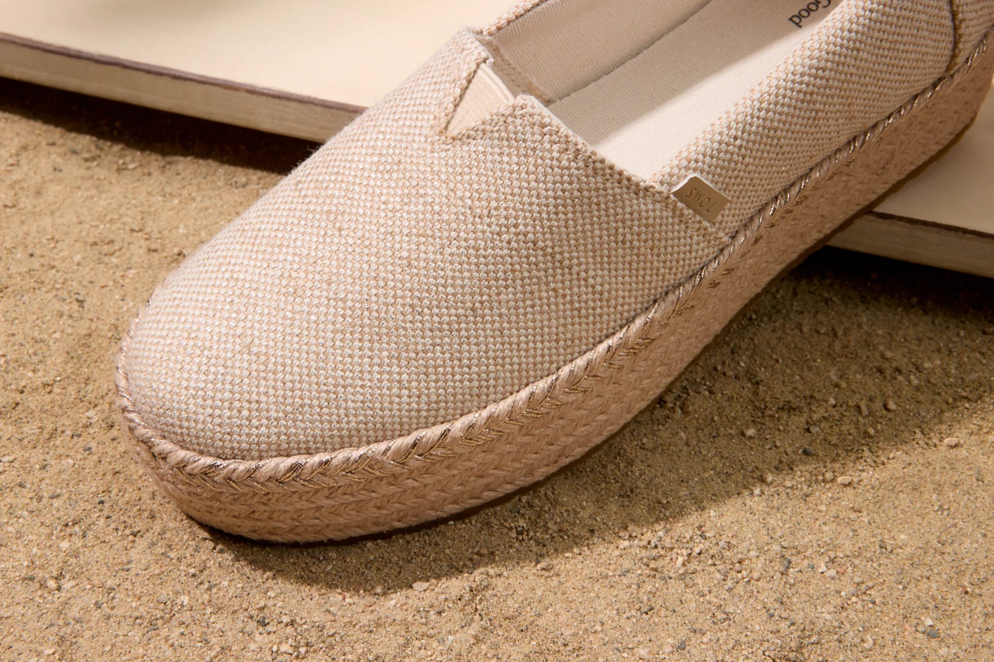 Lässige Canvas-Espadrilles auf einem sandigen Küstenweg bei warmem Nachmittagslicht
