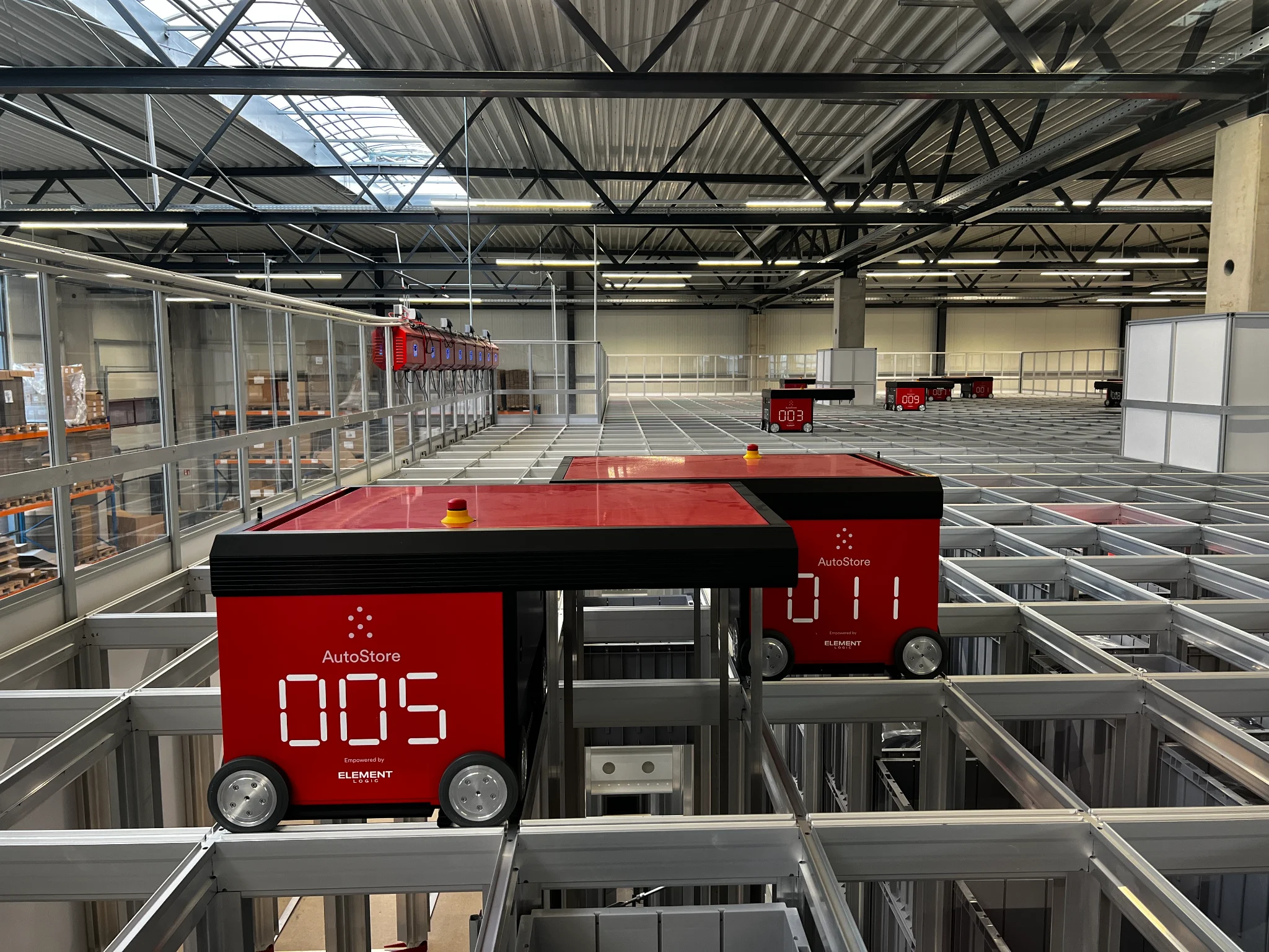 Rote AutoStore-Roboter fahren auf dem Gitter des automatisierten Lagersystems im SportFits Logistikzentrum