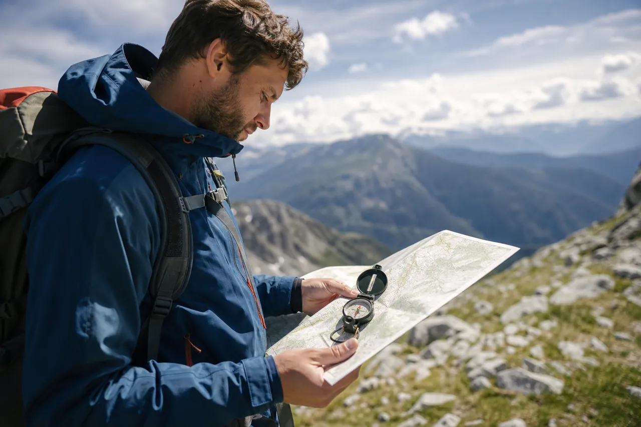 Wanderer mit Karte und Kompass auf einem Bergkamm