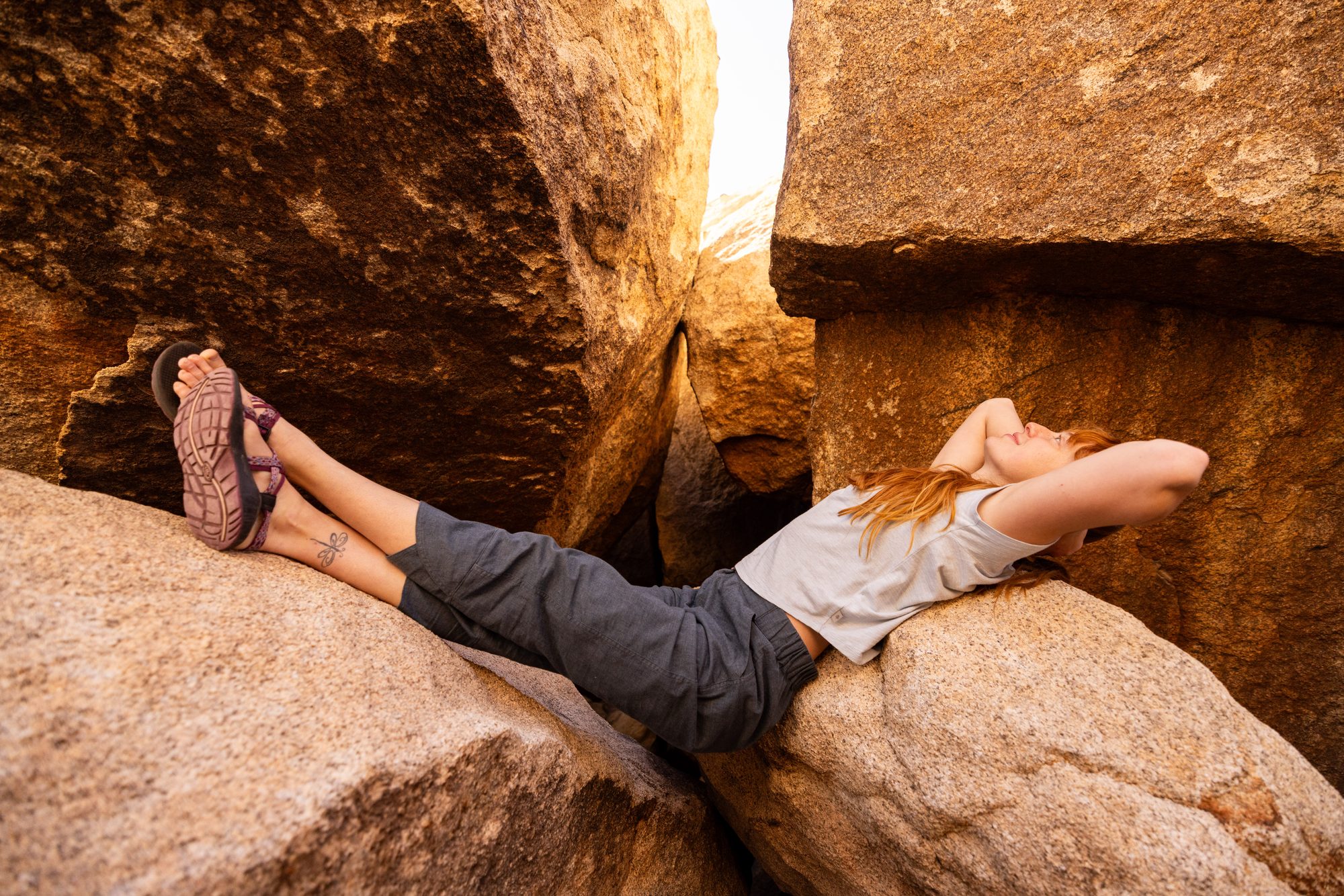 Frau entspannt in Royal Robbins Outdoor-Kleidung auf Felsen in der Wüstenlandschaft